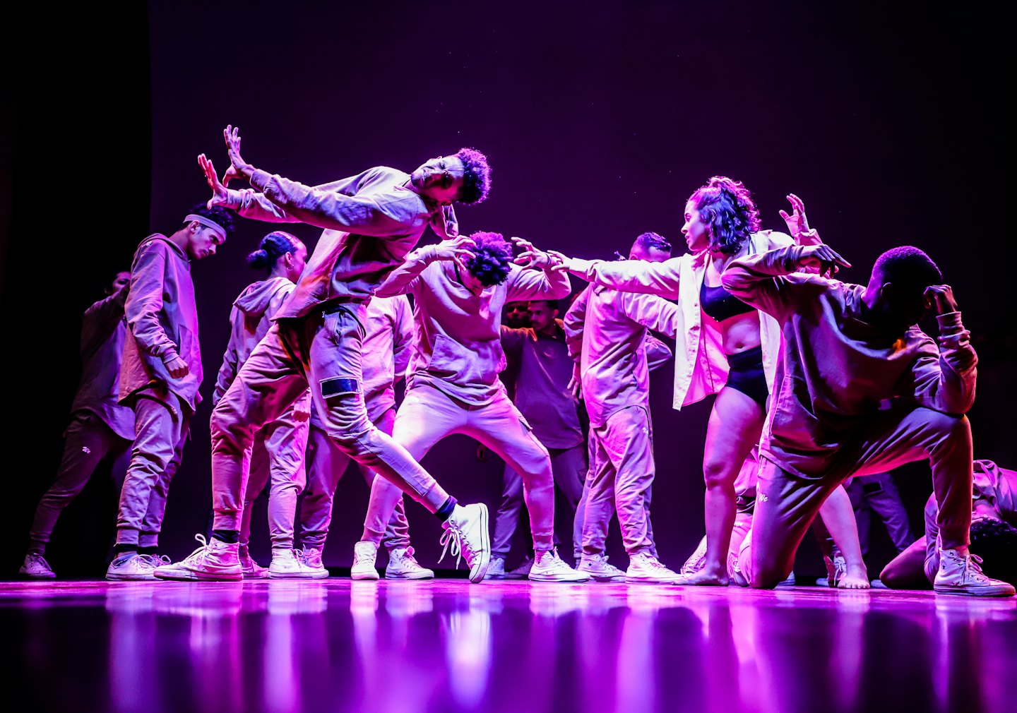 Diverse young dancers in colorful light performing a routine.