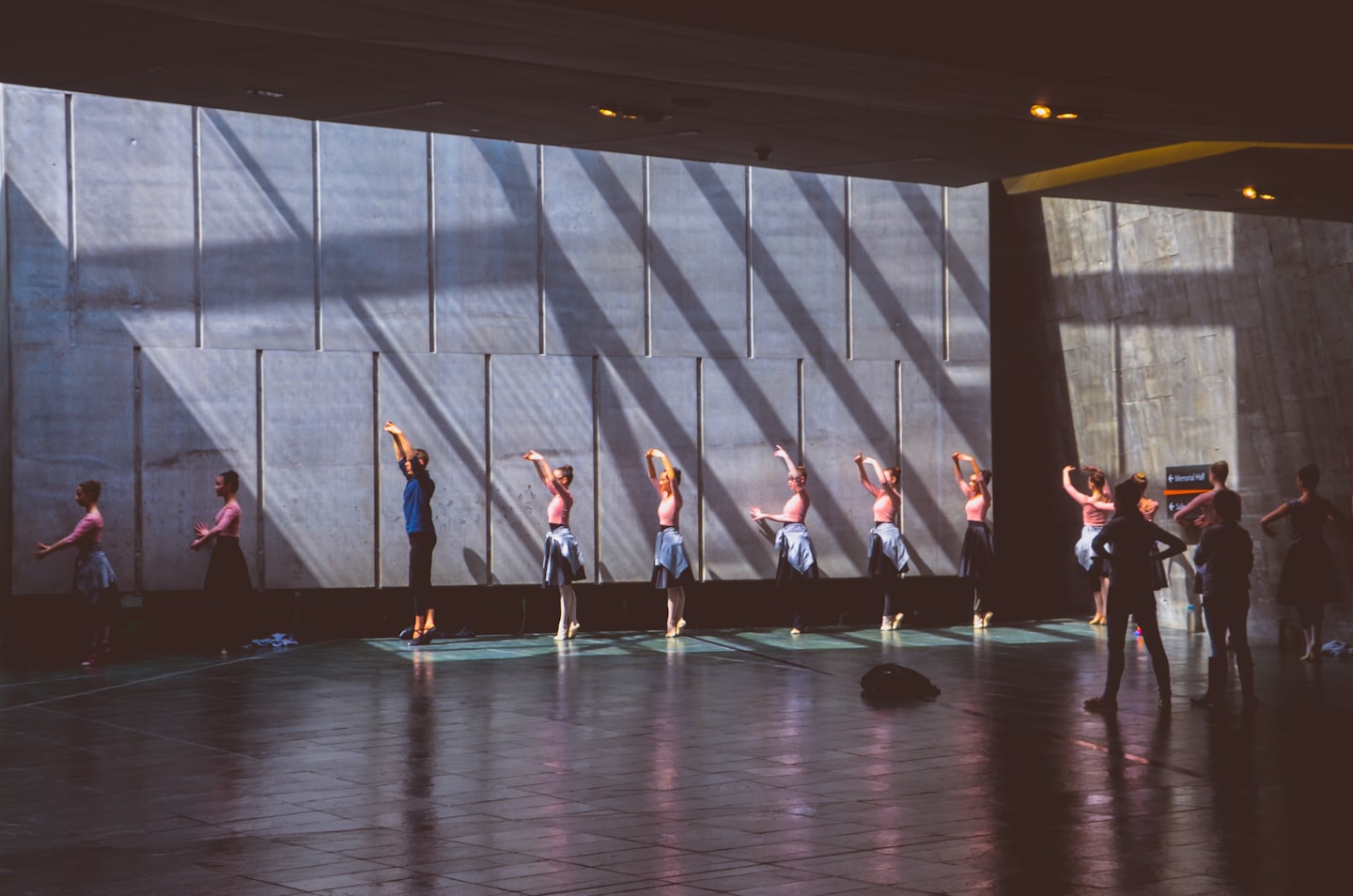Ballet dancers practice poses in a bright, modern studio.