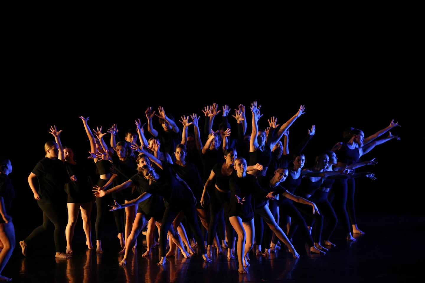 Dancers in black outfits perform an expressive routine on a stage.